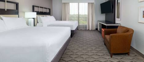 A hotel room with two beds, a TV, a desk, and a chair.