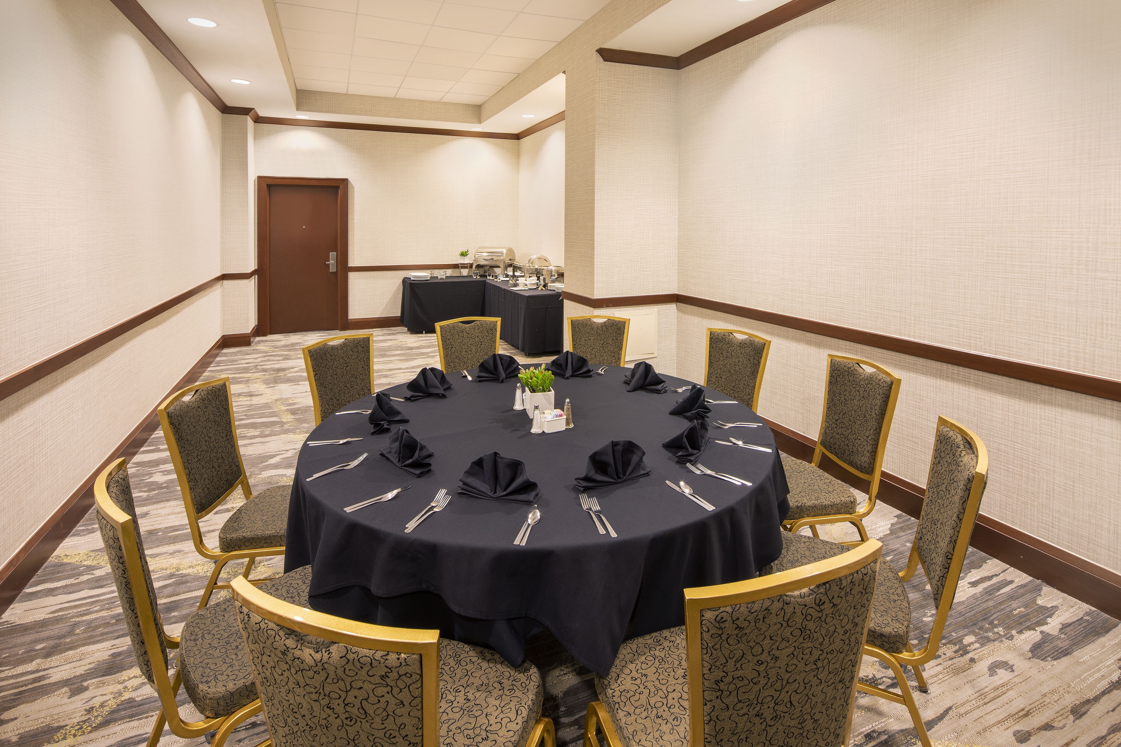 A conference room with a round table, chairs, and a buffet table in the background.