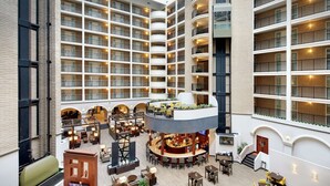 A multi-level hotel atrium with a central bar area, multiple balconies, and a variety of seating arrangements.