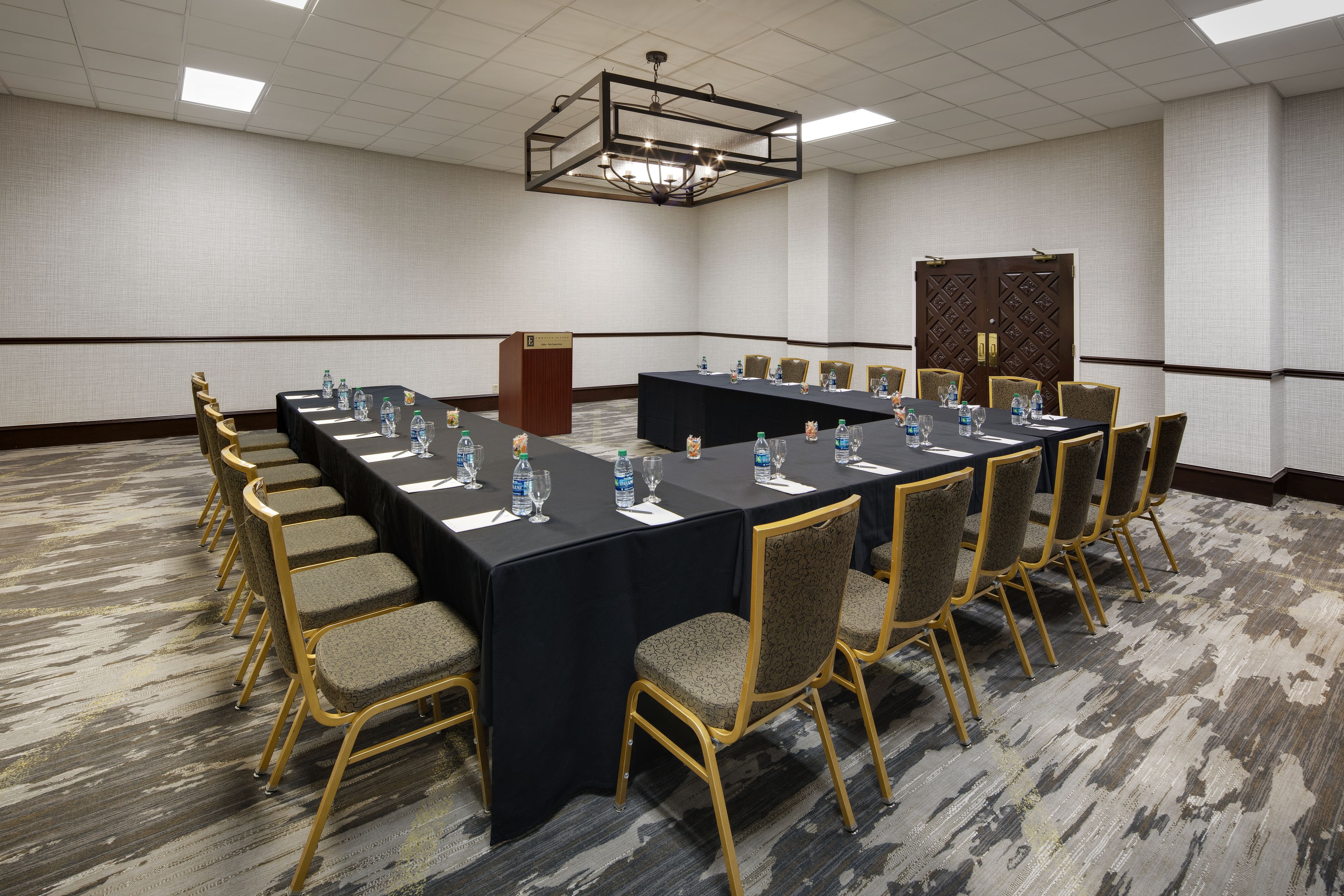 A conference room with a long table, chairs, water bottles, and a podium.