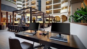 A spacious lobby with multiple seating areas, a central reception desk, and a view of the surrounding multi-story building.