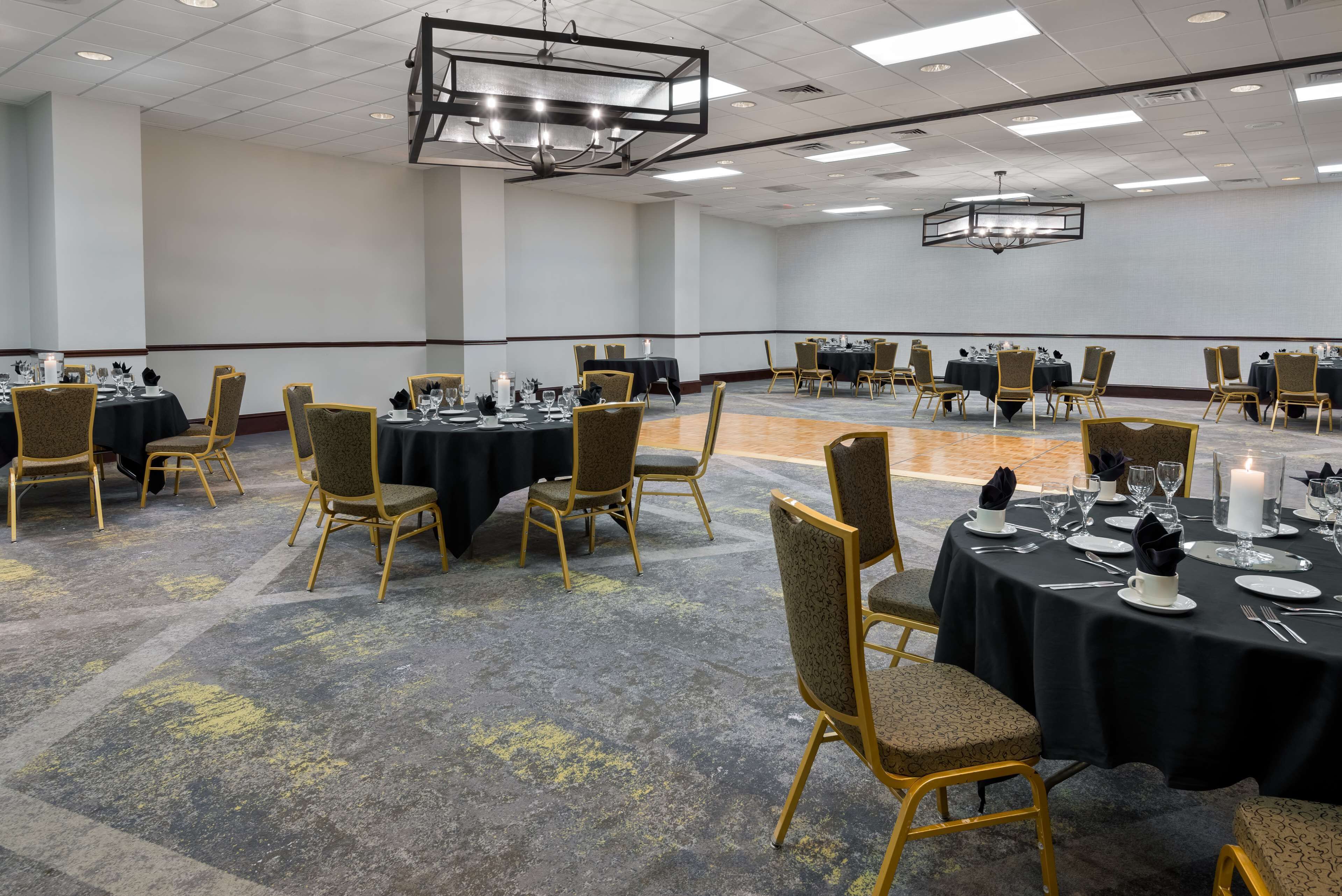 A conference room with round tables, chairs, and a carpeted floor.