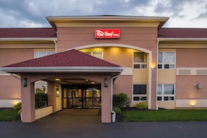Een hotelentree met een rode luifel en een bord met de tekst 'Real Roof Inn'.
