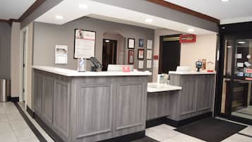 A reception area with two counters, framed certificates on the wall, and a trash bin.