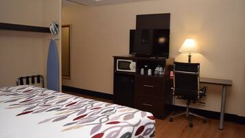 A hotel room with a bed, a desk with a lamp, a television, and a microwave.