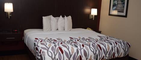 A hotel room with a large bed, two bedside lamps, a nightstand, and a framed picture on the wall.
