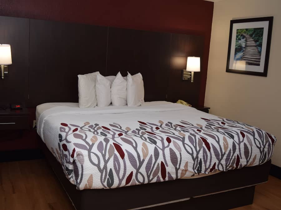 Een hotelkamer met een groot bed, twee bedlampen, een nachtkastje en een lijst met een foto aan de muur.