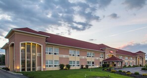 A hotel with a red roof, multiple windows, and a well-maintained lawn. - Red Roof Inn Batavia (Batavia)