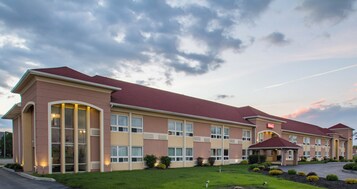 Un hotel con techo rojo, varias ventanas y un c ésped bien cuidado.