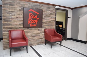 Letrero de Red Roof Inn en una pared de ladrillo, dos sillones de cuero rojo y un letrero de centro de negocios.