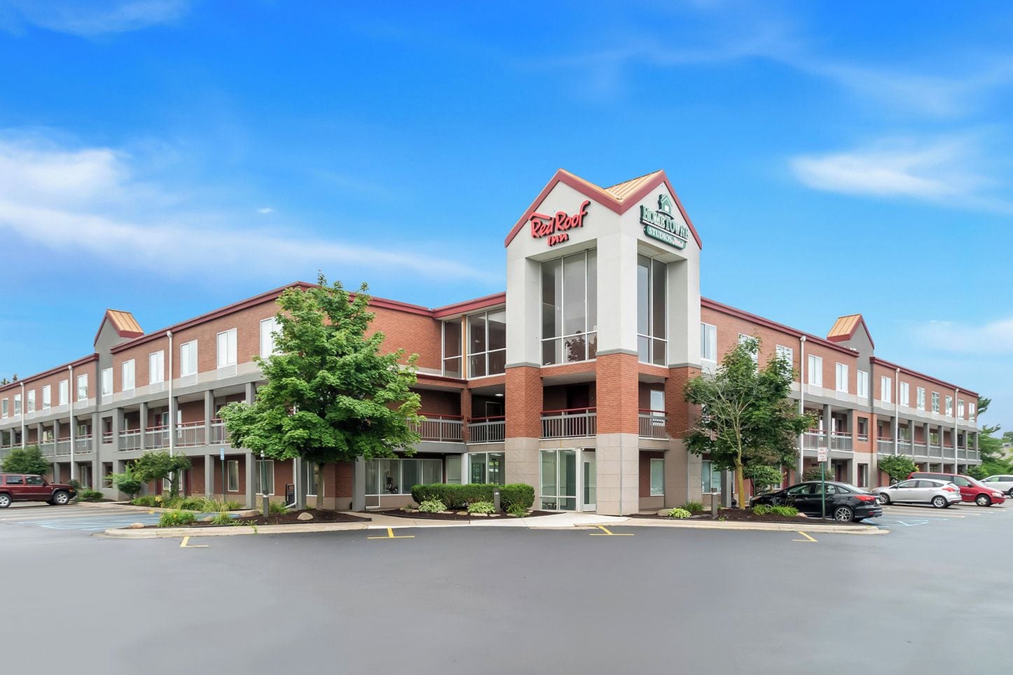 A RealRoof Inn with a brick facade, multiple balconies, and a parking lot.
