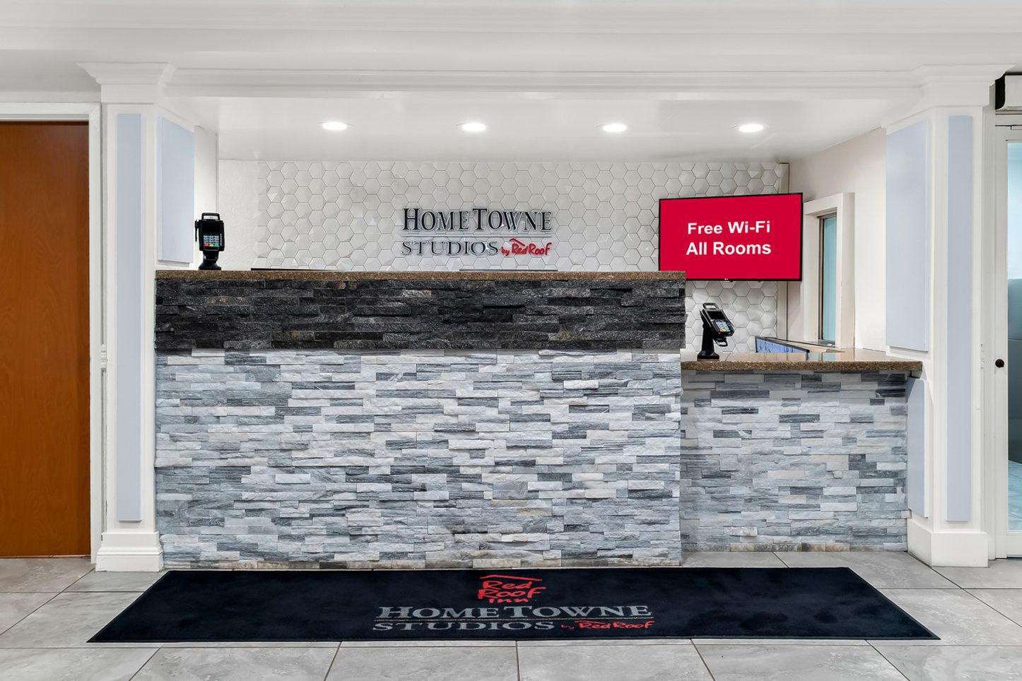 A reception desk with a stone facade, a digital display, and a sign indicating free Wi-Fi in all rooms.