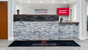 A reception desk with a stone facade, a digital display, and a sign indicating free Wi-Fi in all rooms. - HomeTowne Studios by Red Roof Auburn Hills (Auburn Hills)