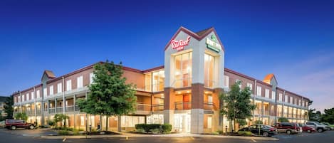 A hotel with a central tower, multiple balconies, and a parking lot.