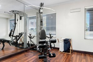 Un gimnasio con equipo de ejercicio, un espejo y piso de madera.
