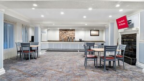 A spacious dining area with a stone backsplash, a kitchen counter, and a fireplace. - HomeTowne Studios by Red Roof Auburn Hills (Auburn Hills)