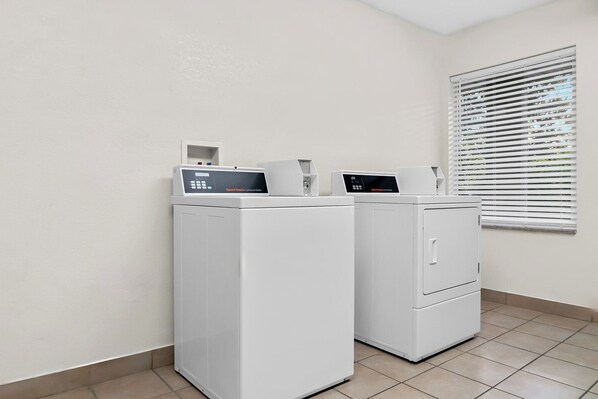 Una sala de lavandería con dos lavadoras blancas y un panel de control.