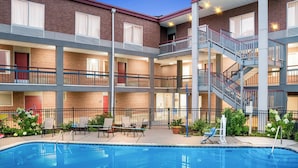 A multi-story hotel with a pool, outdoor seating, and a staircase connecting the floors. - HomeTowne Studios by Red Roof Auburn Hills (Auburn Hills)