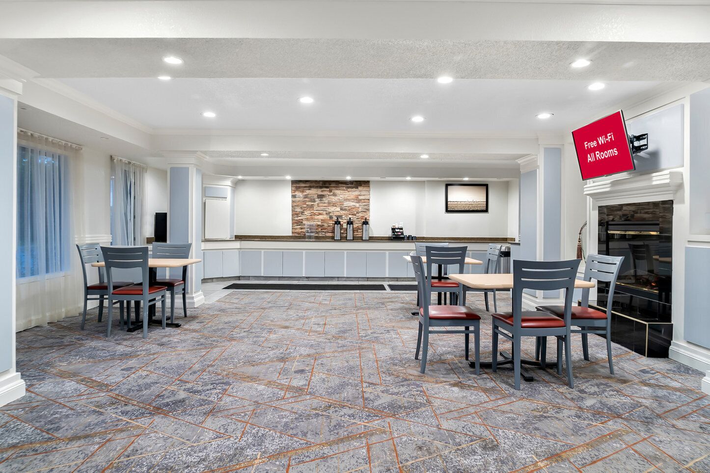 A spacious dining area with a stone backsplash, a kitchen counter, and a fireplace.