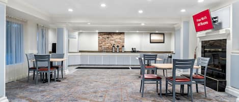 A spacious dining area with a stone backsplash, a kitchen counter, and a fireplace.