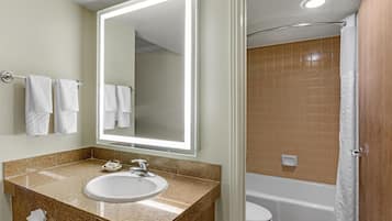 A bathroom with a sink, mirror, and a shower area.