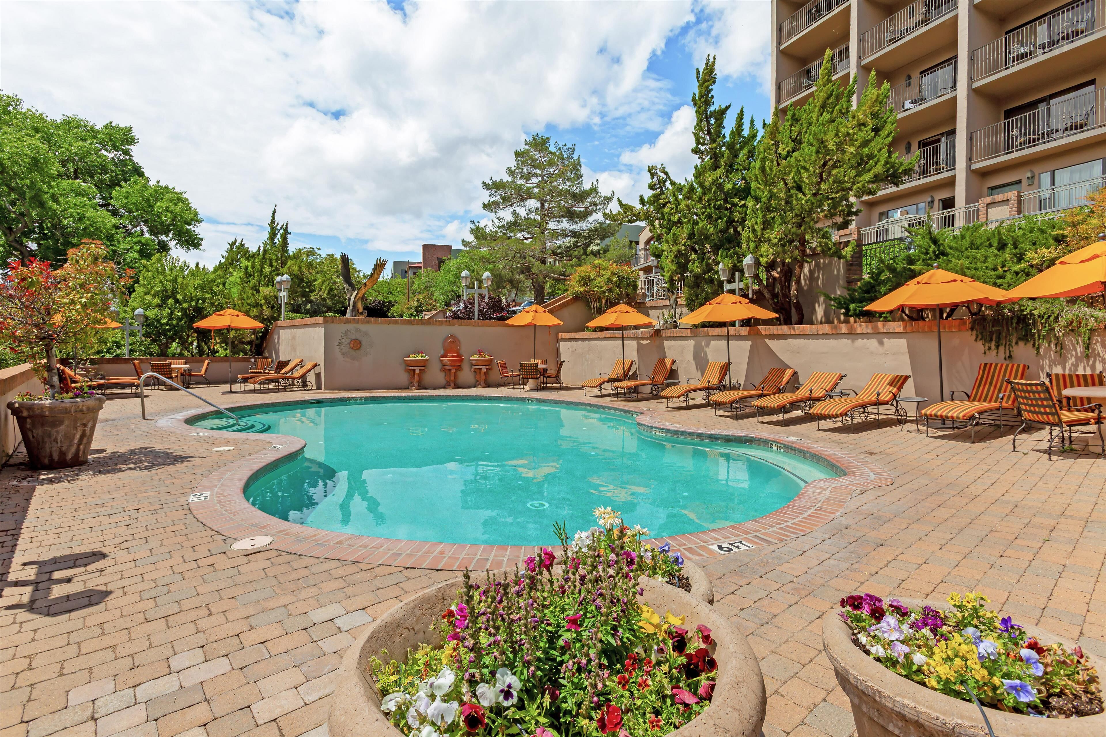 A pool area with lounge chairs, umbrellas, and flower planters.