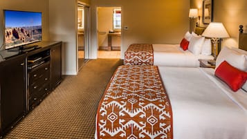 A hotel room with two beds, a television, a desk, and a bathroom visible through an open door.