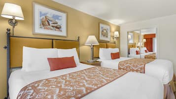 A hotel room with two beds, a large mirror, and artwork on the walls.