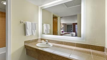 A hotel bathroom with a sink, mirror, and towels on the wall.