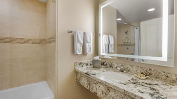 A bathroom with a bathtub, a sink with a marble countertop, and a large mirror.