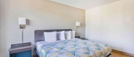 Un lit bien fait, recouvert d’une couvre-lit à motifs, deux tables de chevet avec des lampes et un plancher en bois.