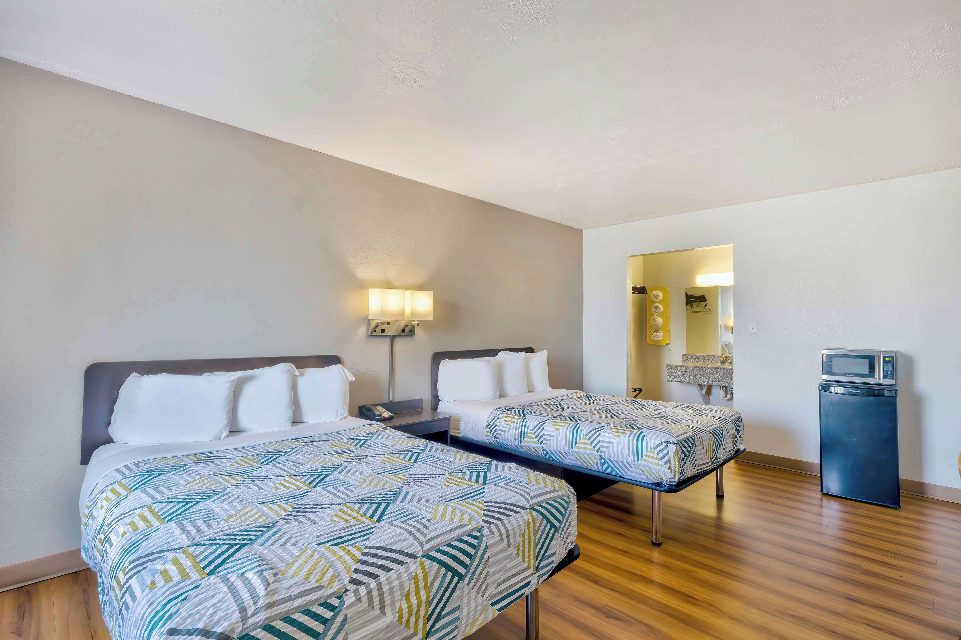 Habitación de hotel con dos camas, un escritorio pequeño, microondas y un espejo.