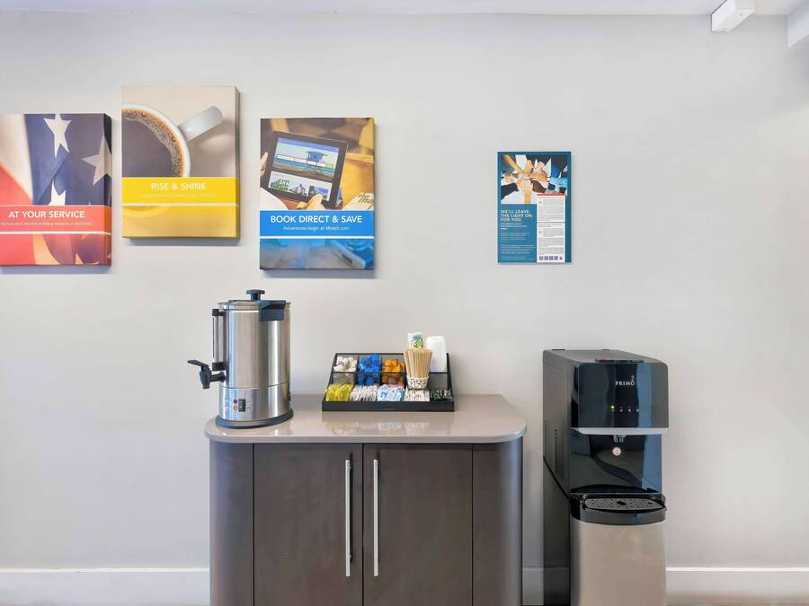 A reception area with a coffee machine, a water dispenser, and informational posters on the wall.