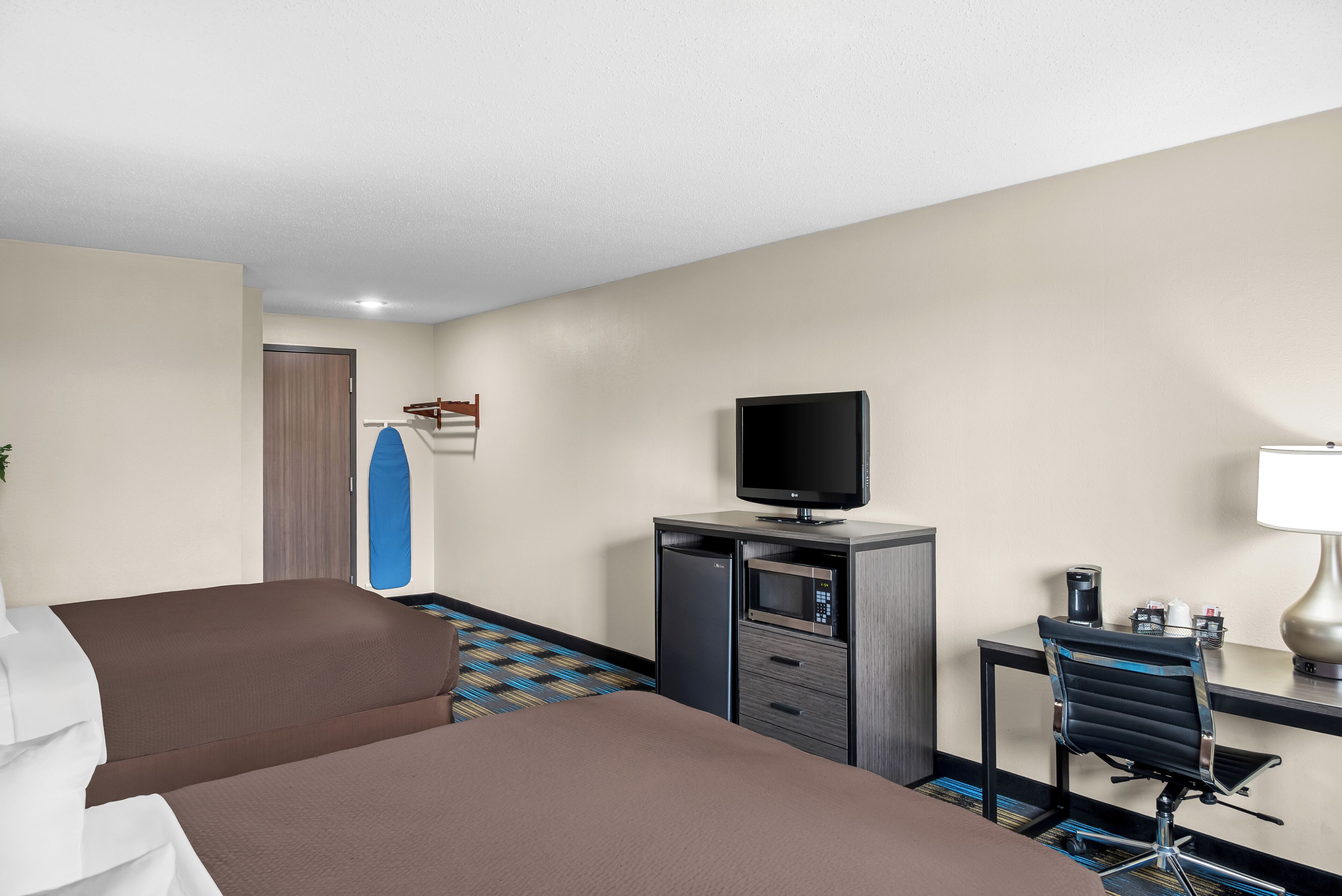 Una camera d'albergo con un letto, una scrivania con un computer, una televisione e un forno a microonde.