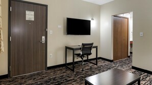 A hotel room with a desk, chair, and a flat-screen TV mounted on the wall.
