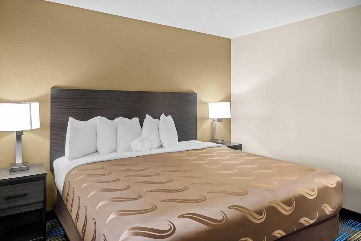 A hotel room with a large bed, two bedside tables, and a nightstand.