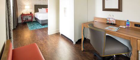A hotel room with a bed, desk, chair, and a wardrobe.