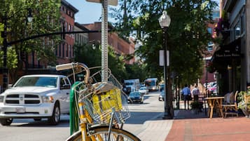 Una bicicleta con una cesta y una bolsa verde estacionada en una acera.