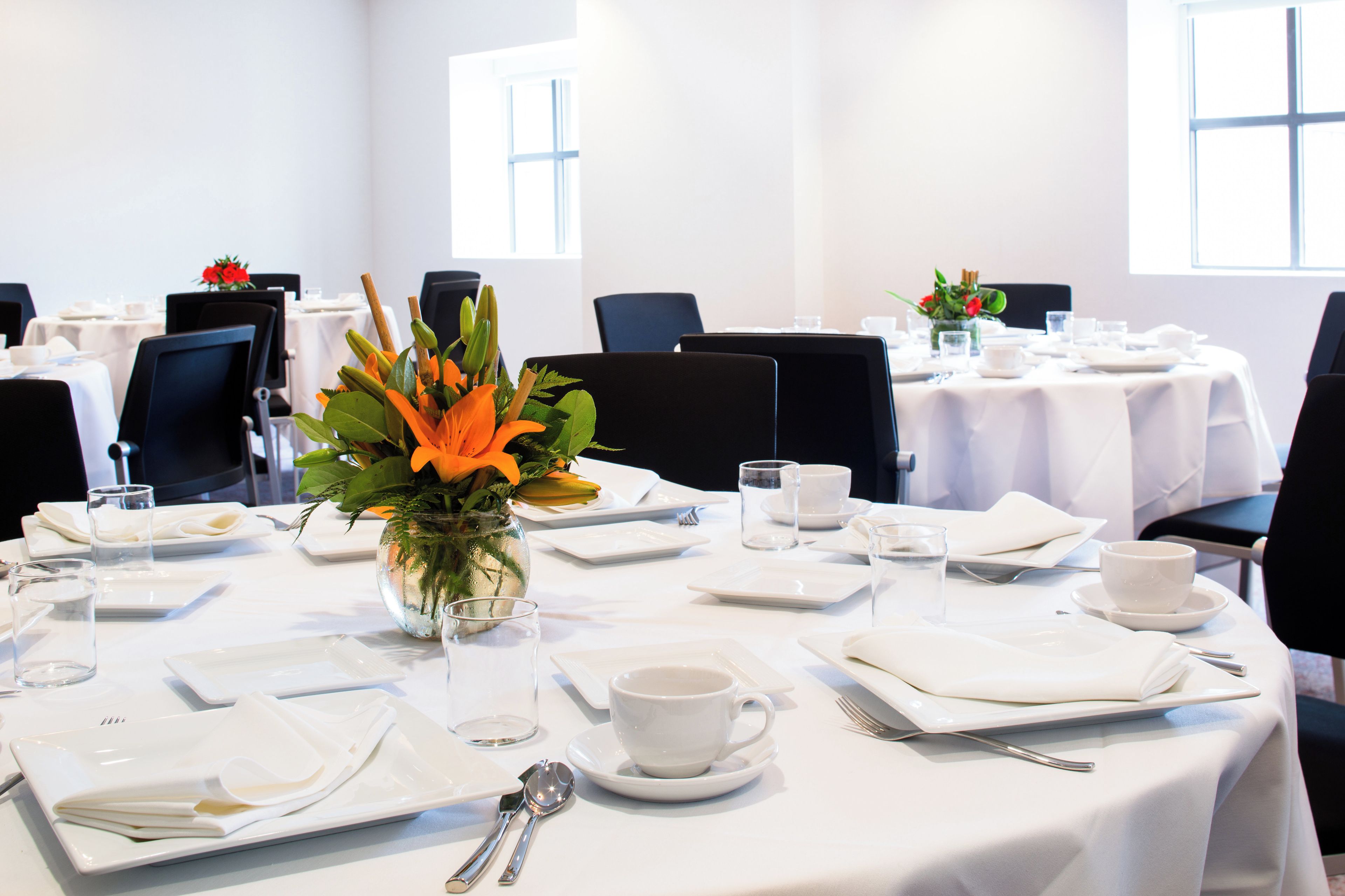 A conference room with round tables, chairs, and a central floral arrangement.