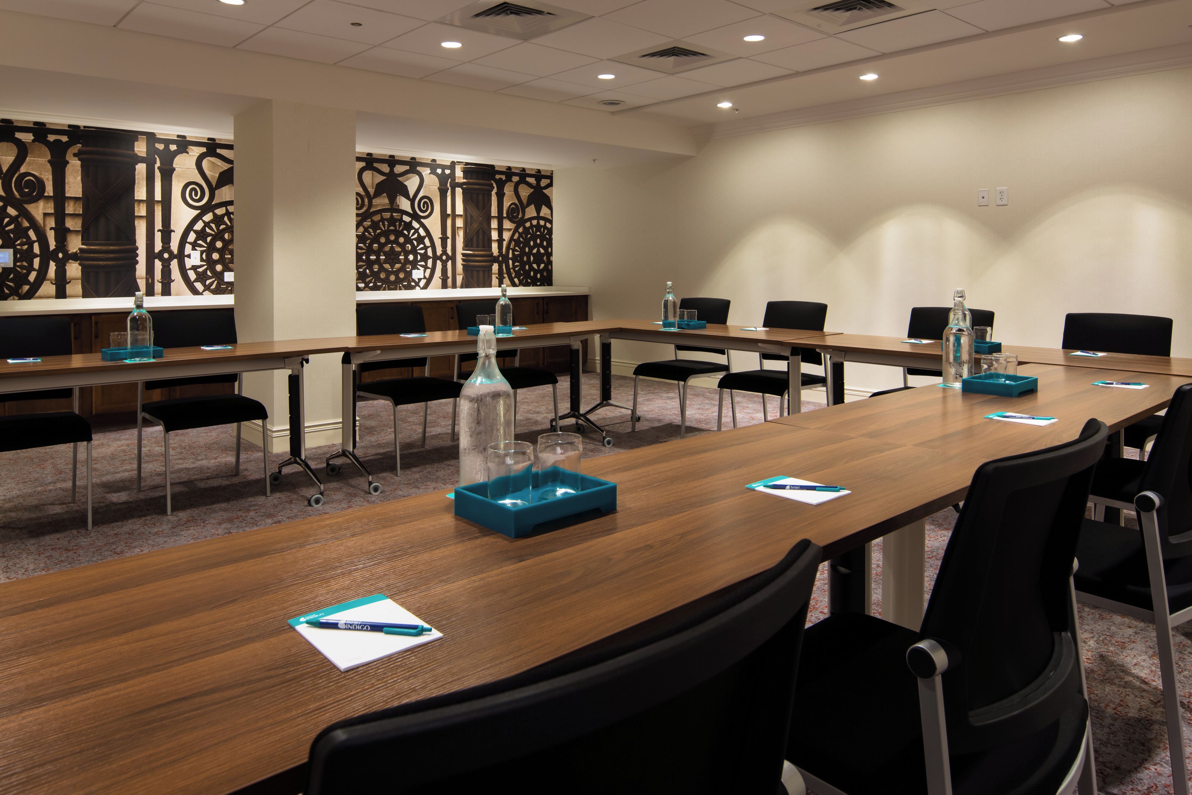 A conference room with a long table, chairs, and a decorative wall panel.