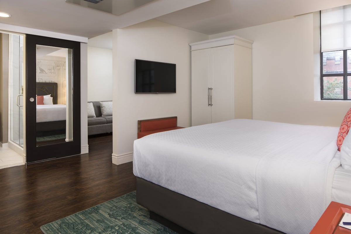 Une chambre à coucher avec un grand lit, une armoire, un téléviseur et une vue sur l’extérieur par une fenêtre.