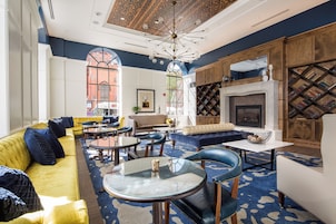 Un área de lounge moderna con chimenea, disposición de asientos y alfombra estampada.