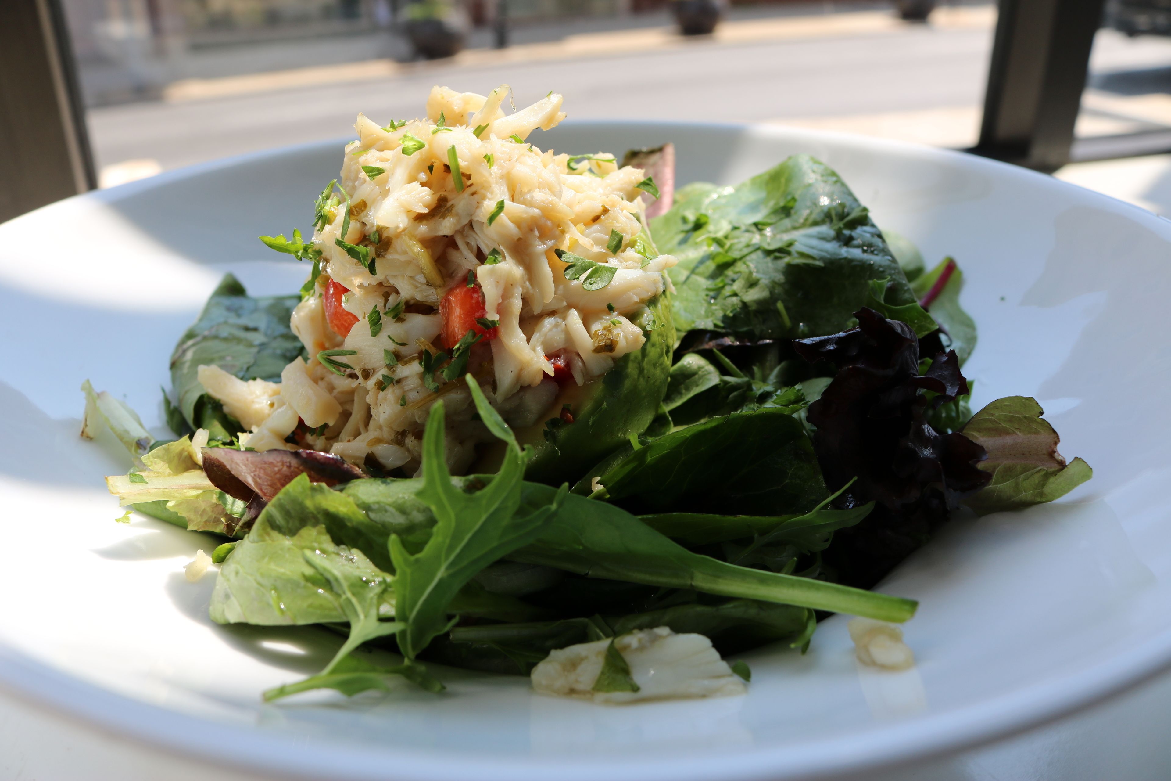 A plate of food with a salad and a creamy topping.