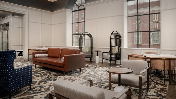 A spacious lobby with a large window, a brown leather sofa, a blue armchair, and a round table. - Hotel Indigo Baltimore Downtown by IHG (Baltimore)