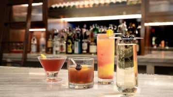 Drei Cocktails auf einer Bar, im Hintergrund verschwommen Flaschen.