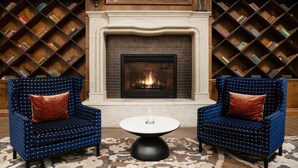A room with two blue armchairs, a white round table, a fireplace, and bookshelves filled with books. - Hotel Indigo Baltimore Downtown by IHG (Baltimore)