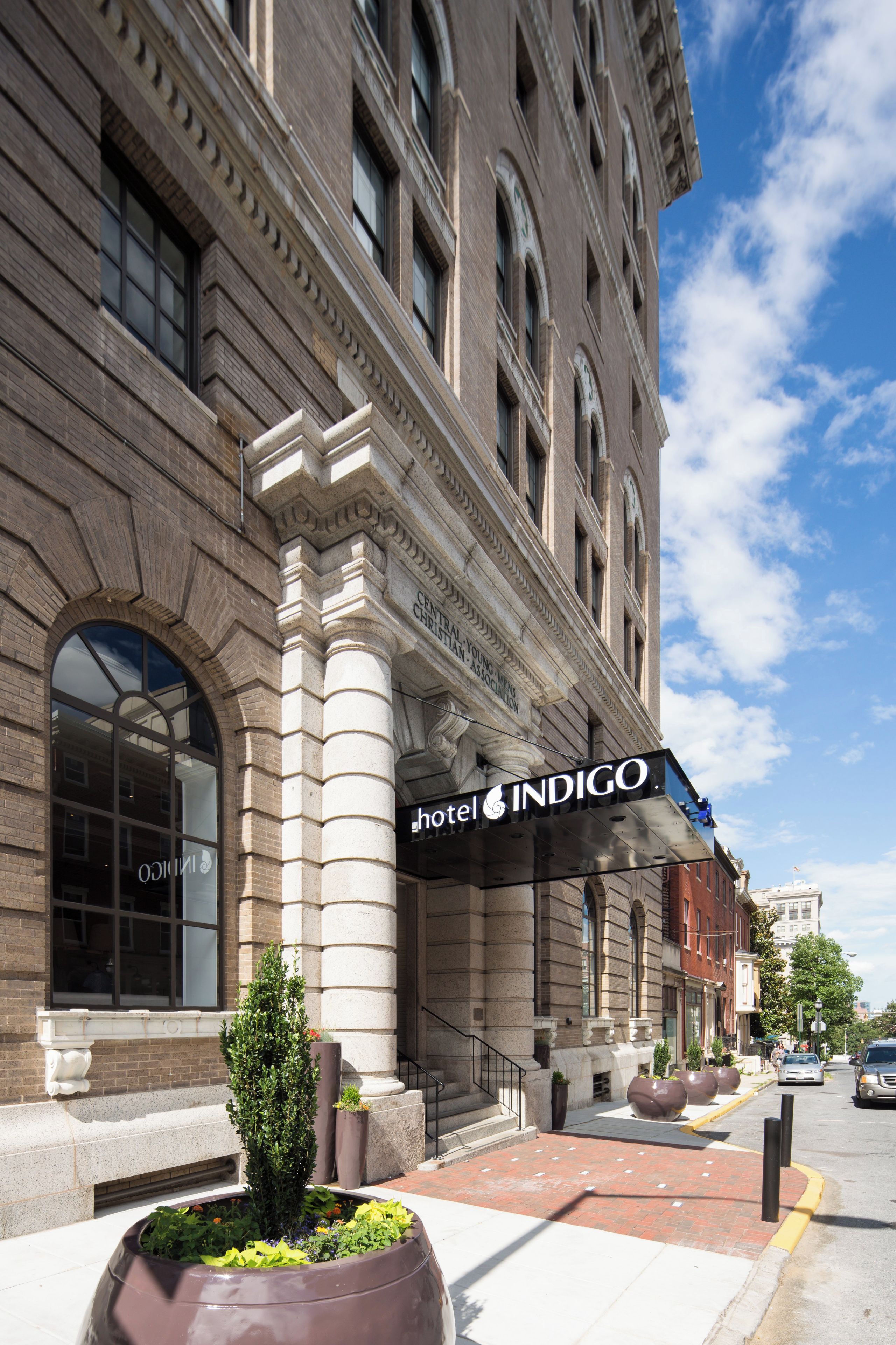 Un hotel con fachada clásica, ventanas amplias y un cartel llamativo que dice 'hotel INDIGO'.