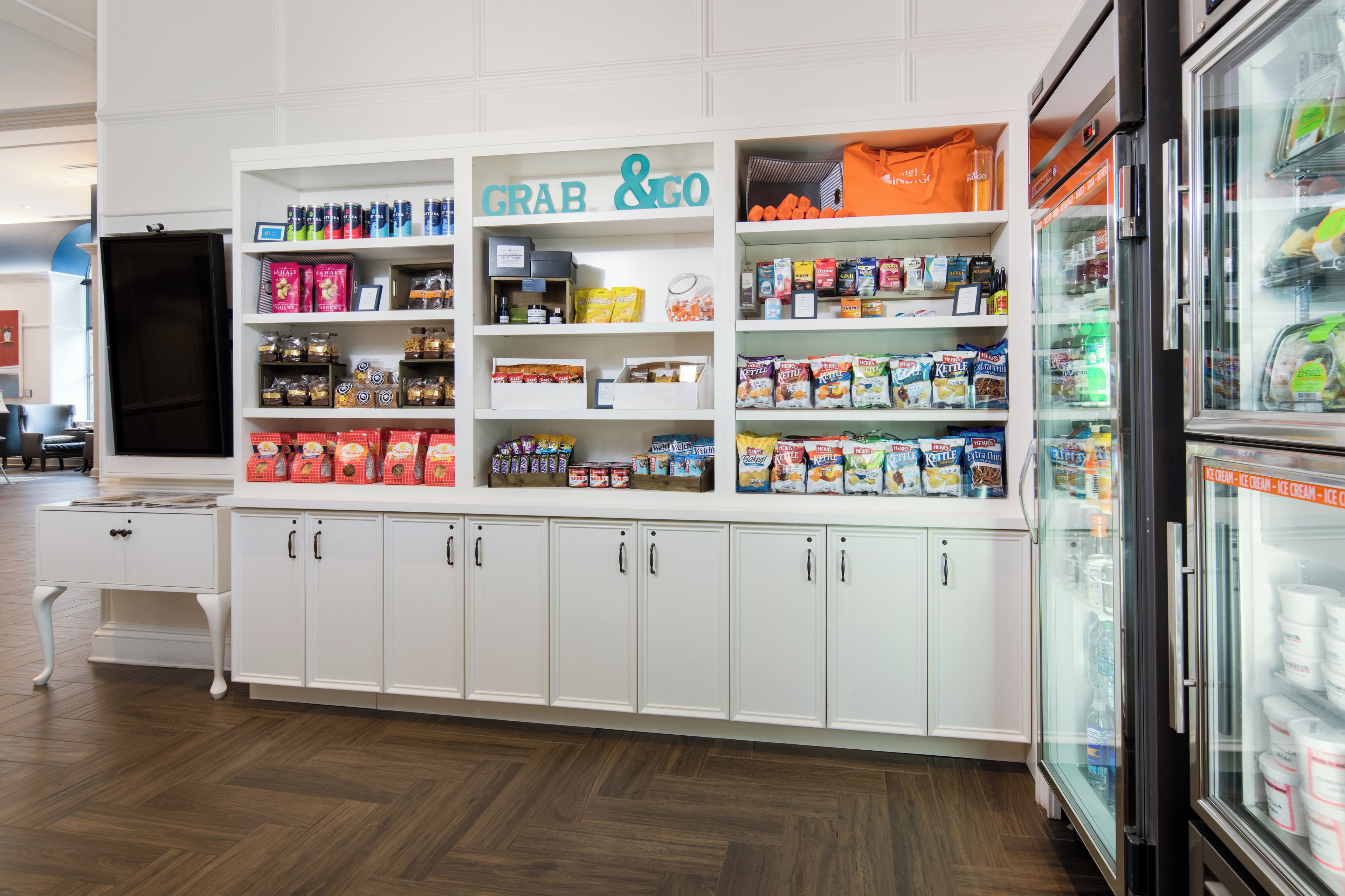 A grocery store interior with shelves stocked with various products, a refrigerated section, and a 'Grab & Go' sign.