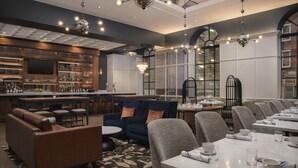 Un ristorante moderno con zona bar, posti a sedere e un lampadario.