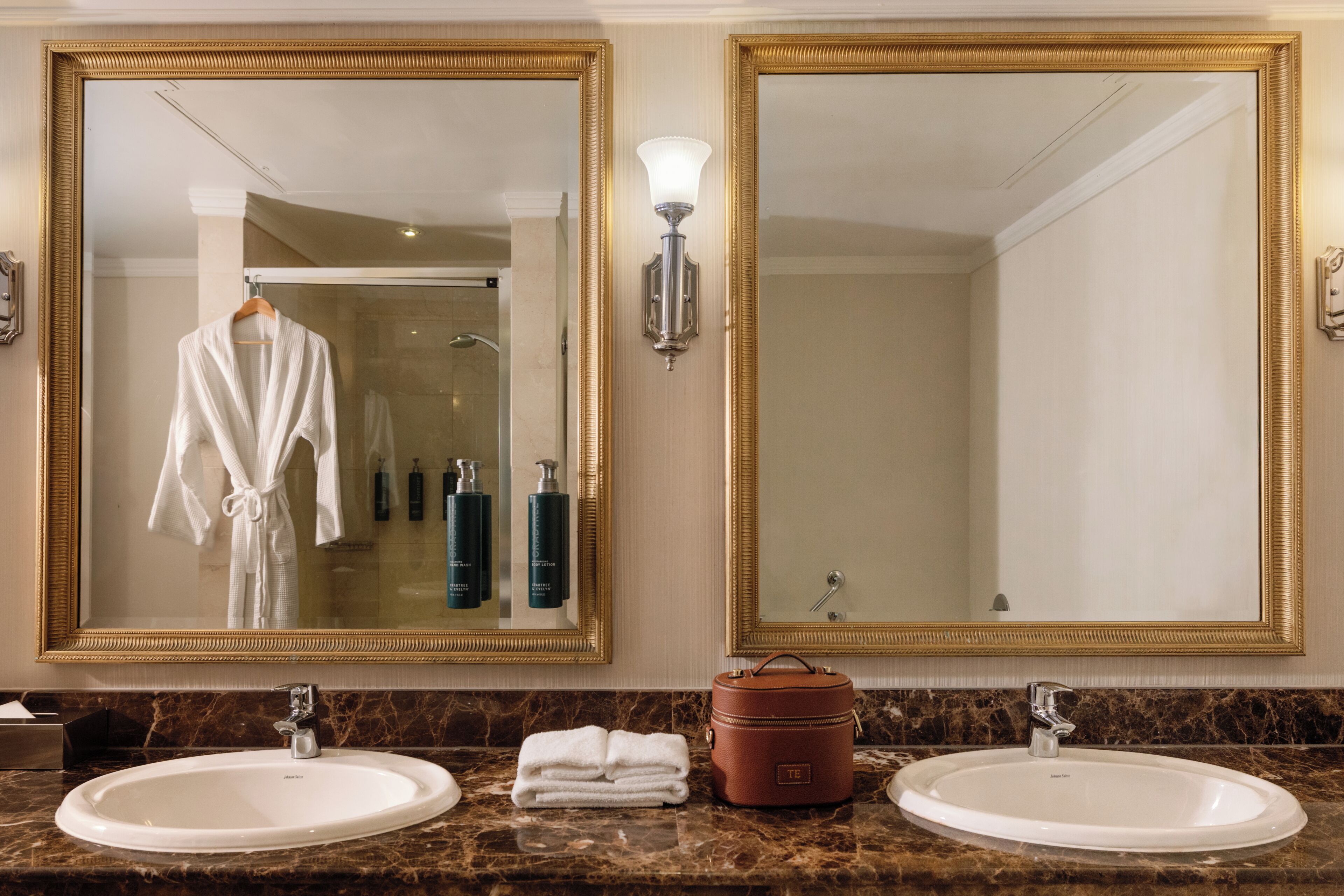 A bathroom with two sinks, a robe, a towel, and a toiletry bag.